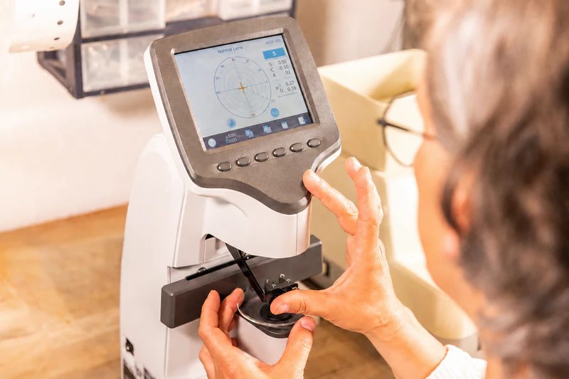 Optician positioning eyeglasses on an auto lensmeter for prescription measurement